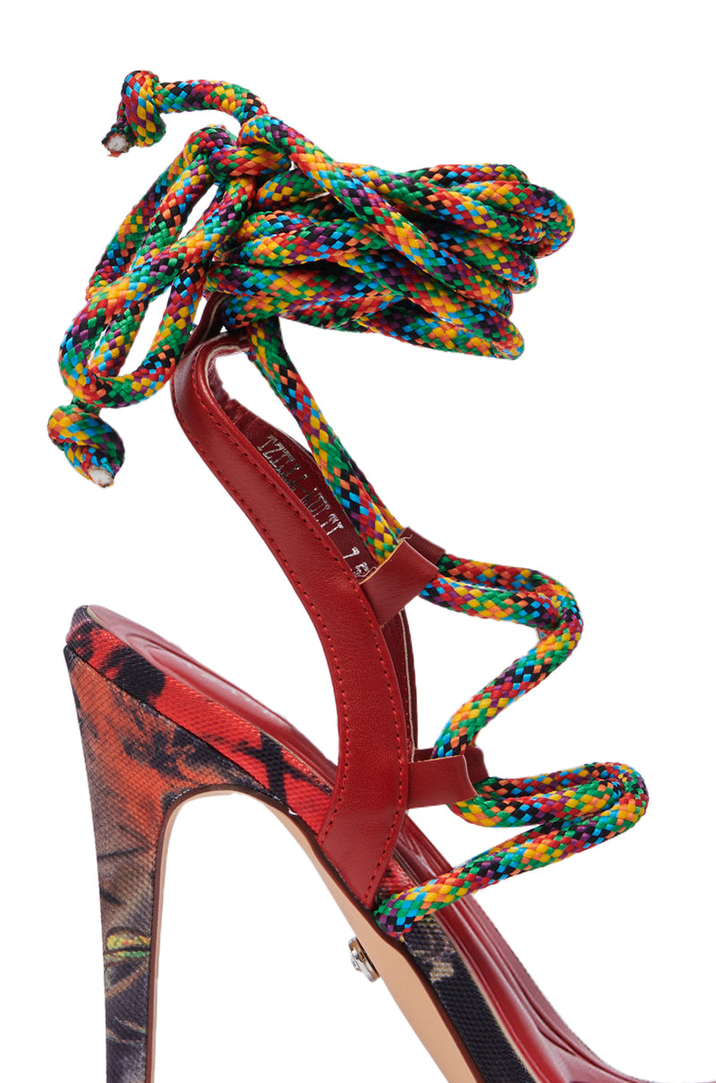 The AZALEA WANG TZILLA MULTI COLOR ROPE STILETO SANDAL features red leather straps, a multicolor braided rope lace-up design wrapping the ankle, and a vibrant abstract patterned heel and sole for a bold look.