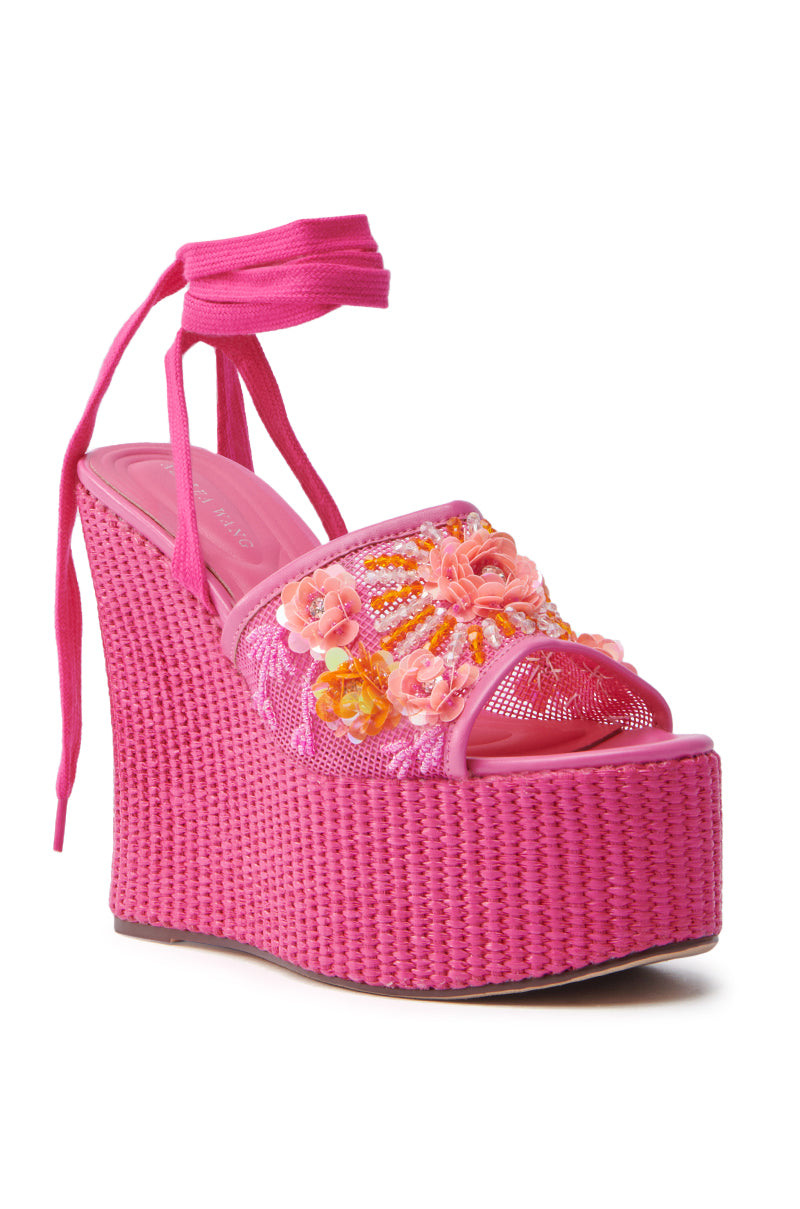 The AZALEA WANG VONDA PINK WEDGE SANDAL has a high, woven texture platform sole and adjustable ankle wrap ties. It features intricate floral embellishments with pink and orange flowers on the toe strap, making it a standout piece in any wardrobe.