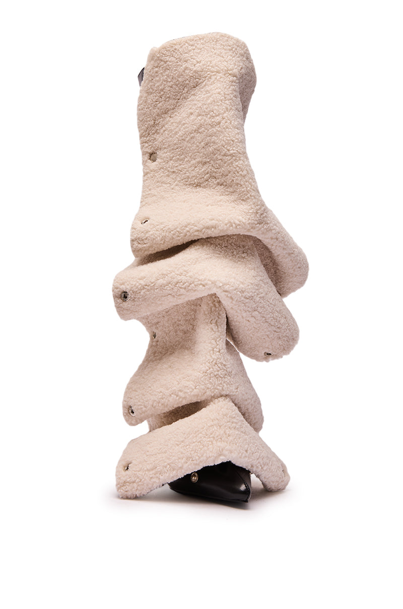 The AZALEA WANG VULTURE BLACK SHERPA LINED BOOT is a beige, sculptural knee-high boot featuring textured fleece-like material and wavy layered flaps over a black base, shown upright against a white background.