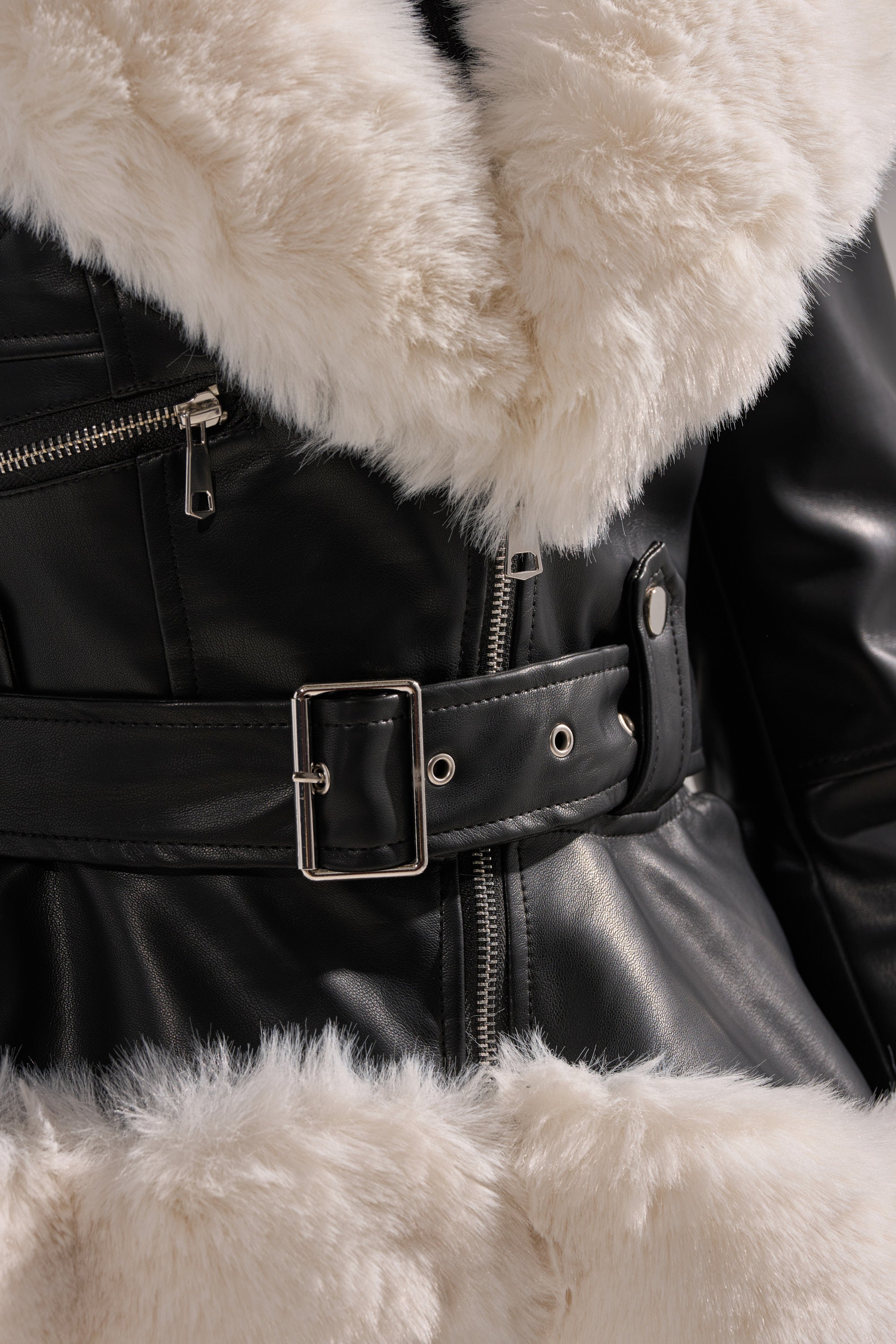 Close-up of the BABY IT'S COLD OUTSIDE FUR TRIM MOTO jacket in black faux leather with a wide, fluffy white faux fur collar and trim, silver zipper, belt buckle, and snap button accents.