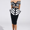 The individual wears the WAITING FOR YOU MIDI SKIRT, featuring a black and white off-the-shoulder dress with geometric patterns, a fitted top with cut-outs, and a bodycon silhouette. They pair it with black pointed shoes against a plain backdrop.