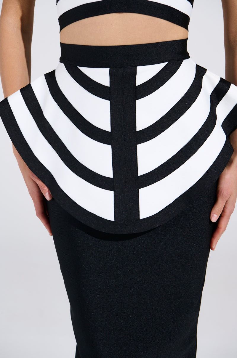 A close-up of someone in the "WAITING FOR YOU MIDI SKIRT" displays a bodycon silhouette. Bold curved stripes adorn the top, with a flared peplum overlay at the waist, and a solid black skirt. Hands rest elegantly at their sides.
