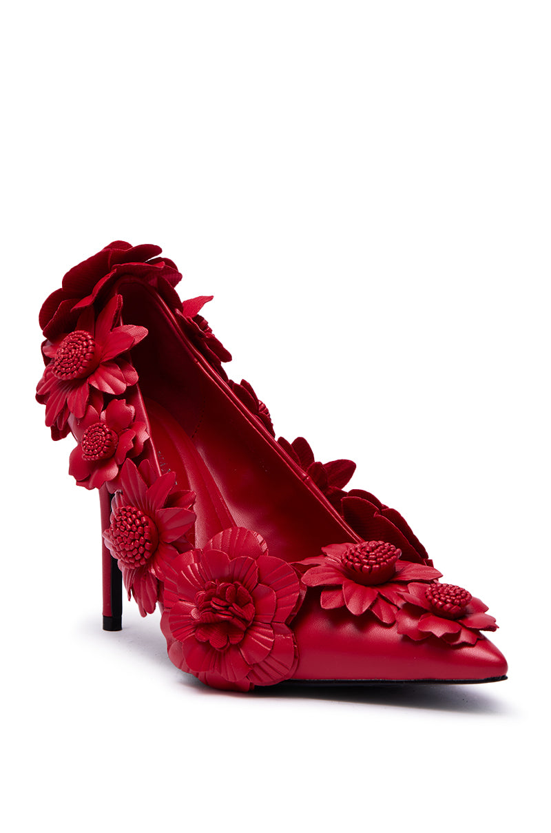 The AZALEA WANG ZARAH RED FLOWER PUMP features a stiletto heel and detailed red floral appliqués on the heel, sides, and toe, all set against a plain white background.