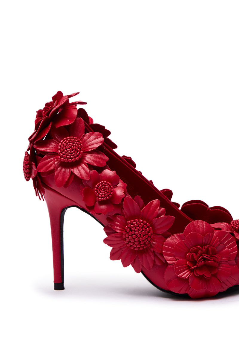The AZALEA WANG ZARAH RED FLOWER PUMP features a stiletto heel and bold red flower appliqués on faux leather along the sides, back, and heel, all set on a crisp white base.