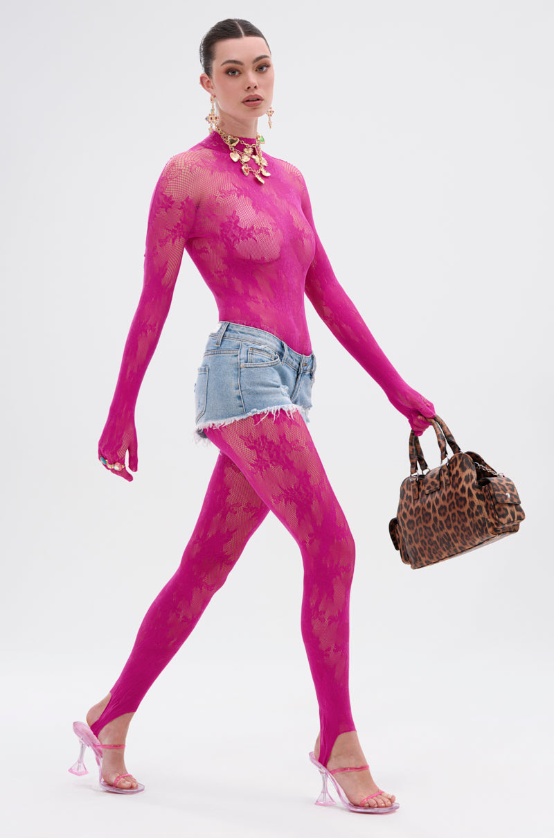 A person walks confidently in the MAIN MOMENT STRETCH LACE JUMPSUIT—a sheer hot pink mock neck piece—paired with distressed denim shorts, pink heels, a chunky gold necklace, and a leopard print handbag against a white background.