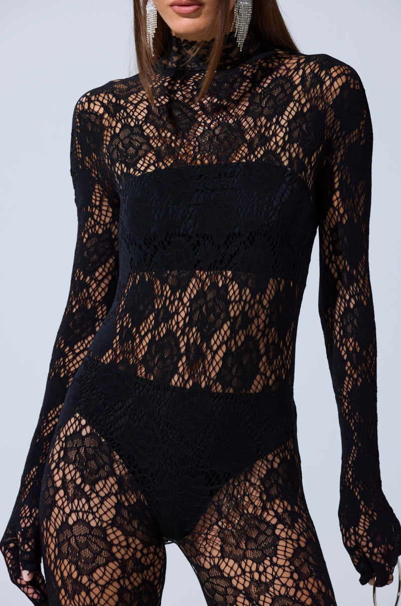 A woman models the FEELIN SPICY STRETCH BODYSTOCKING—a fitted, sheer black lace bodysuit with floral patterns, revealing a strapless black undergarment beneath. Her head is partially out of frame.