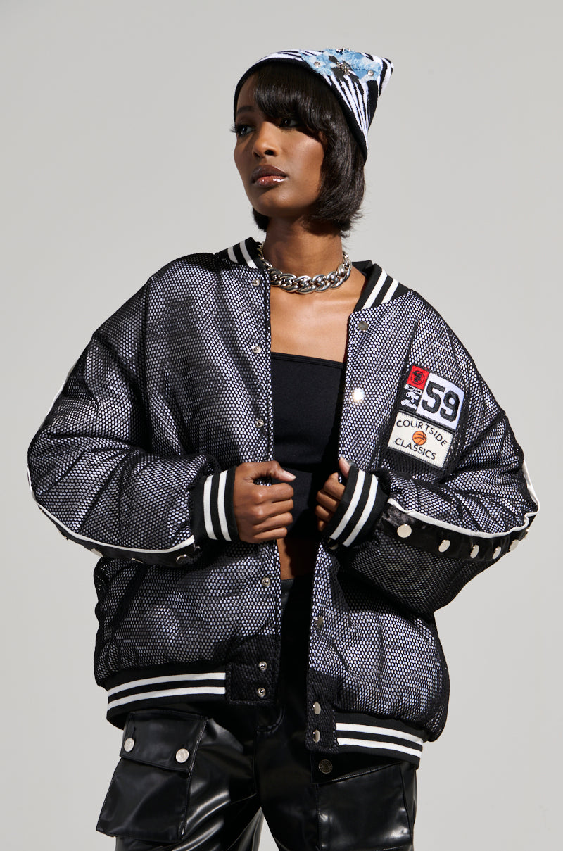 A person wearing the PLAYERS ONLY JERSEY BOMBER, black leather pants, and a patterned beanie. They have short black hair and are posing confidently against a neutral background.
