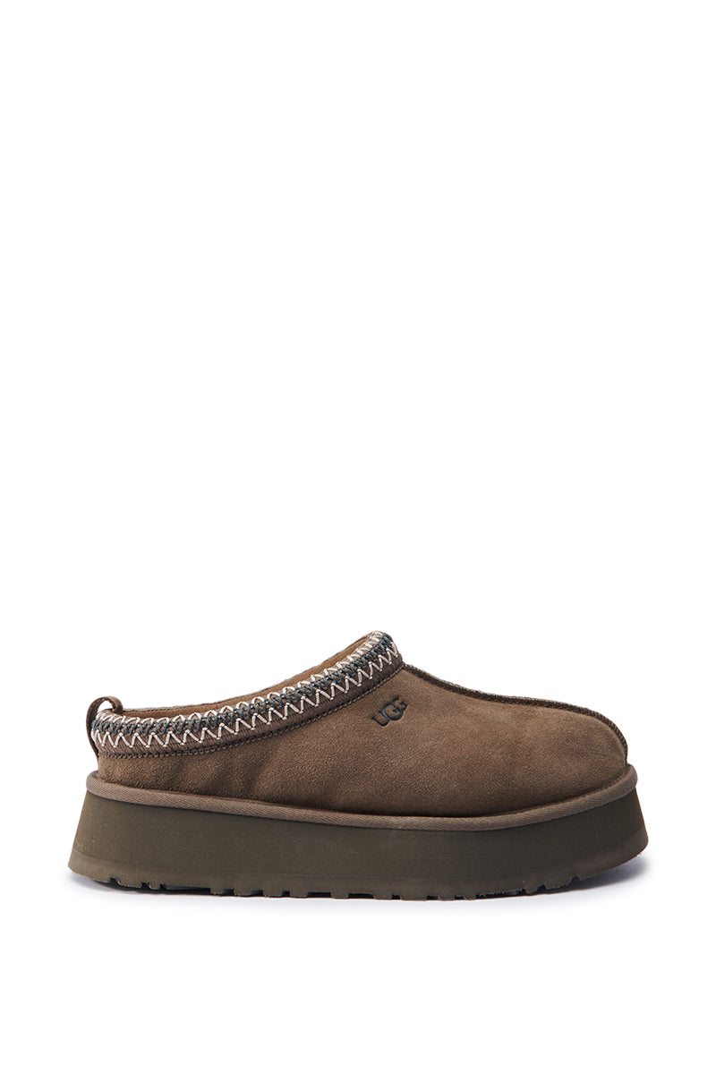 The UGG Tazz in Hickory features a thick sole and textured stitching around the opening, making it perfect for a cozy ensemble. Its minimalist design is enhanced by an embossed logo on the side, making it an ideal addition to any wool blend outfit.