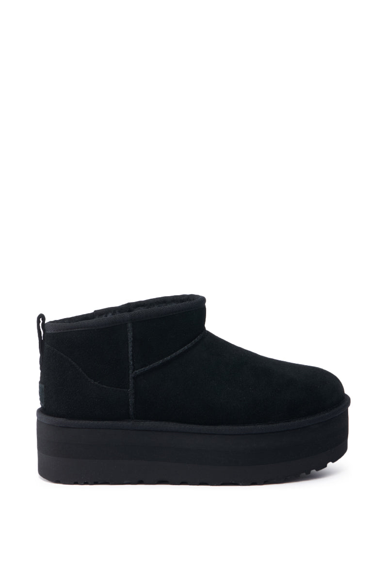 The UGG CLASSIC ULTRA MINI PLATFORM IN BLACK is a suede bootie with a thick sole and wool blend upper designed for extra warmth. It features detailed stitching and a handy pull tab, all presented on a plain white background.