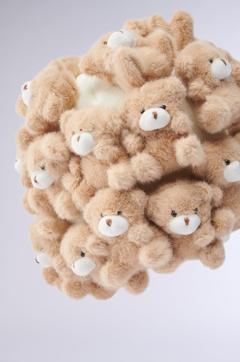 The BEARY BABE BEANIE is a spherical item featuring plush teddy bear appliques, each with white snouts and black eyes, against a plain white backdrop. These densely packed beanie-like bears create a textured, fluffy surface. 5