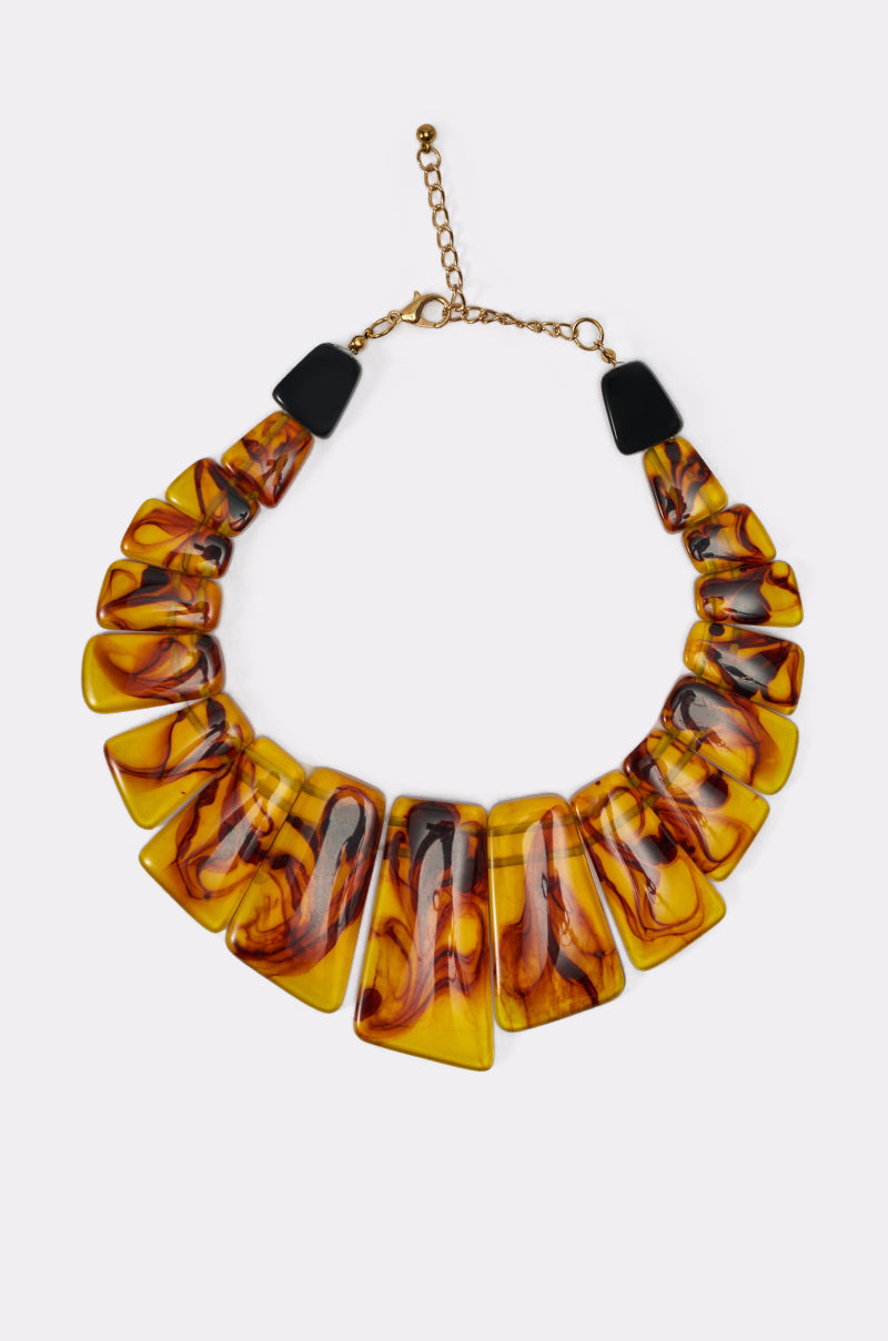 The JUST WANNA PARTY NECKLACE is a bold, chunky resin necklace with rectangular amber pieces featuring black and red swirls, gold links, and an adjustable chain clasp—a striking statement for any outfit. 0
