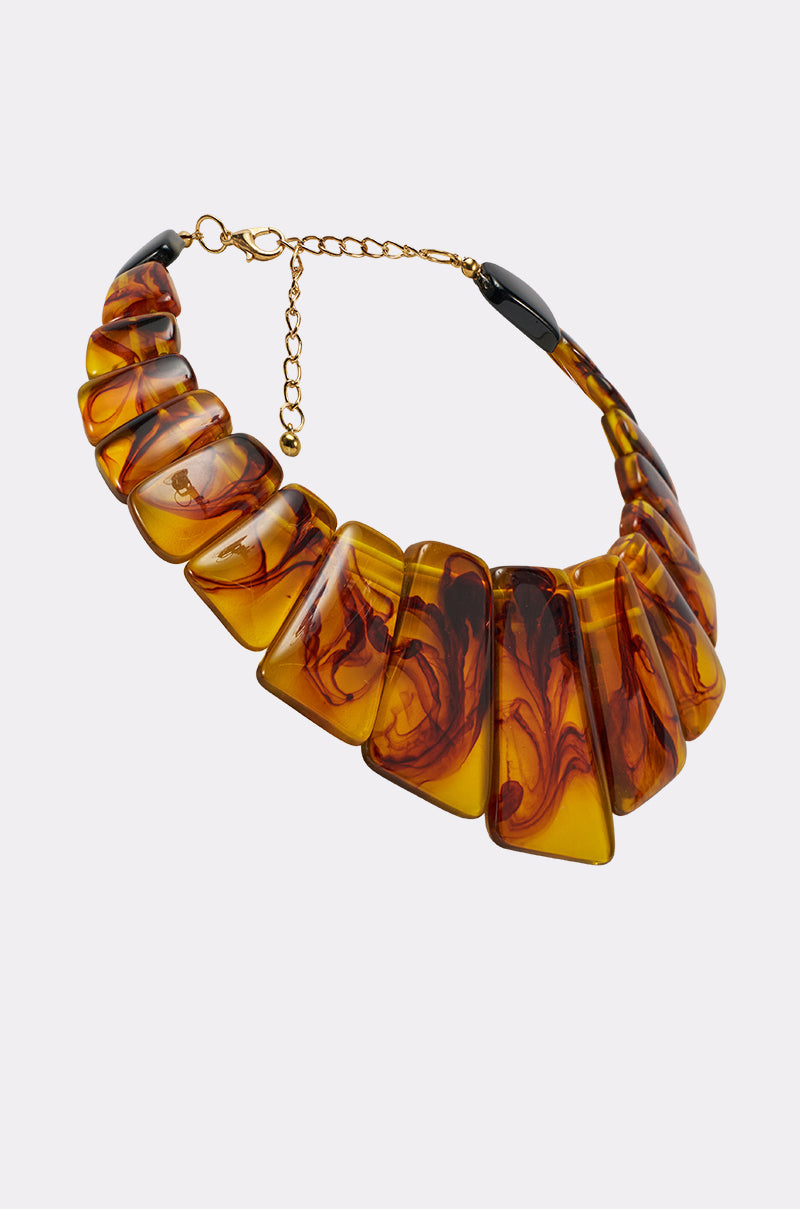 The JUST WANNA PARTY NECKLACE is a chunky resin statement piece with fan-shaped, amber-hued links featuring dark swirls, all connected by gold links and finished with an adjustable gold chain clasp. 2