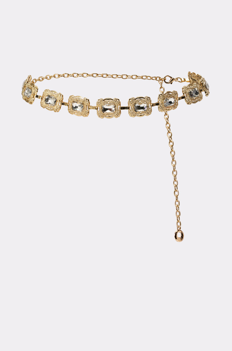 The GODDESS VIBES CHAIN BELT showcases square, textured gold links set with clear gemstones for vintage glam. Its adjustable design features a dangling chain ending in a small gold bead. 0
