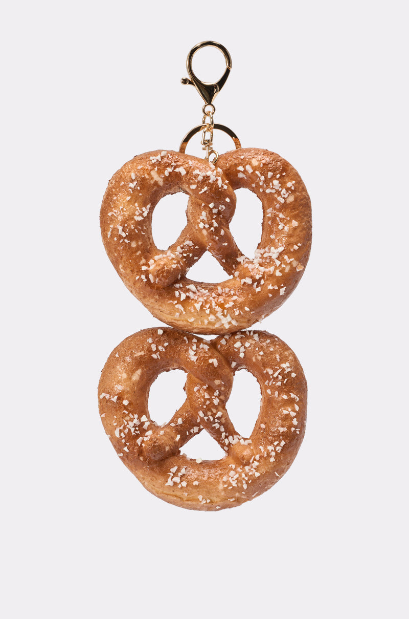 The NEEDED SOME SALT OVERSIZED KEYCHAIN features two salted pretzels stacked vertically and joined by a gold keychain clip, making a playful pretzel accessory displayed on a plain white background. 1