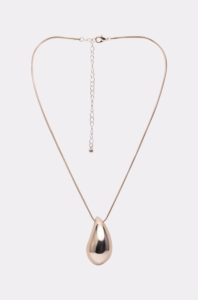 The DESIGNER DREAMING NECKLACE features a gold teardrop pendant on a thin, adjustable chain against a plain light grey background.