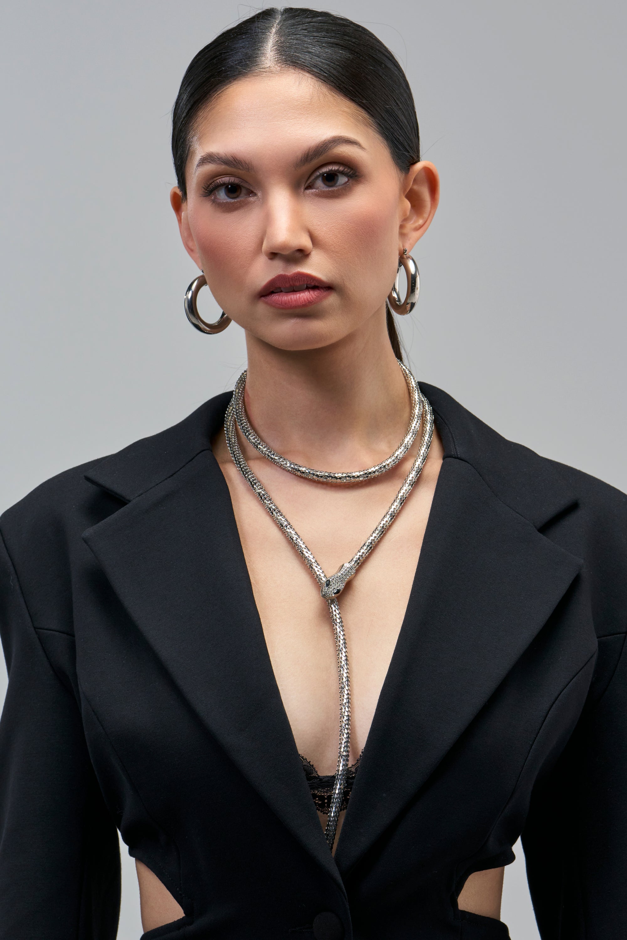 A person wearing a silver SNAKE LAYERED NECKLACE that wraps around the neck as a lariat.