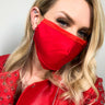 A person with blonde hair is wearing a BASIC BAE TRIPLE LAYER FASHION FACE COVER in bright red, paired with a matching red jacket adorned with silver studs. The person is looking at the camera, showcasing the vibrant color of their outfit.