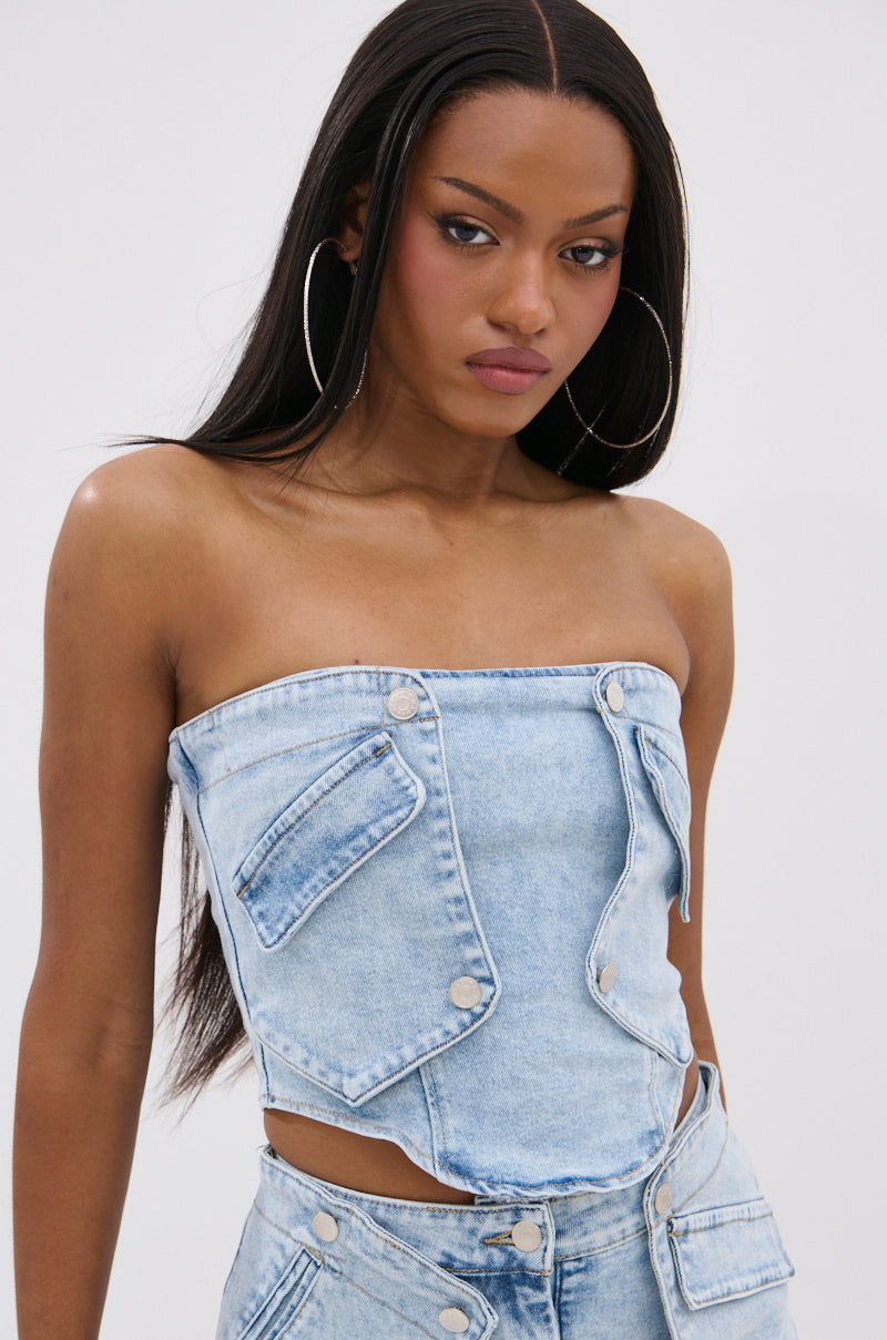 A woman with long straight hair wears the OLIVIA DENIM CORSET and matching pants, styled with large hoop earrings, against a plain light background. 1