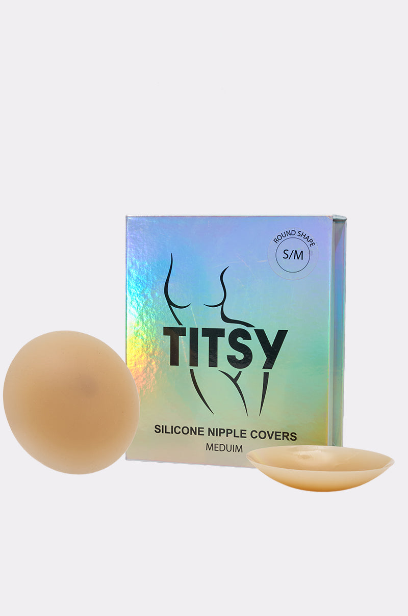 A pair of round, beige TITSY THIN EDGE SILICONE NIPPIE COVERS for seamless breast coverage, shown next to holographic packaging labeled "Medium, S/M, Round Shape.