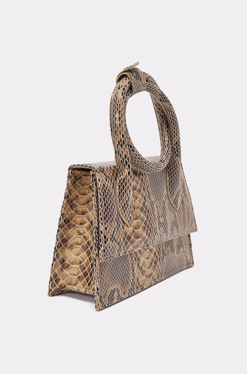 The IN THE WILD PURSE is a brown faux leather snakeskin structured handbag featuring a top handle and flap-over closure, shown against a plain white background. 5