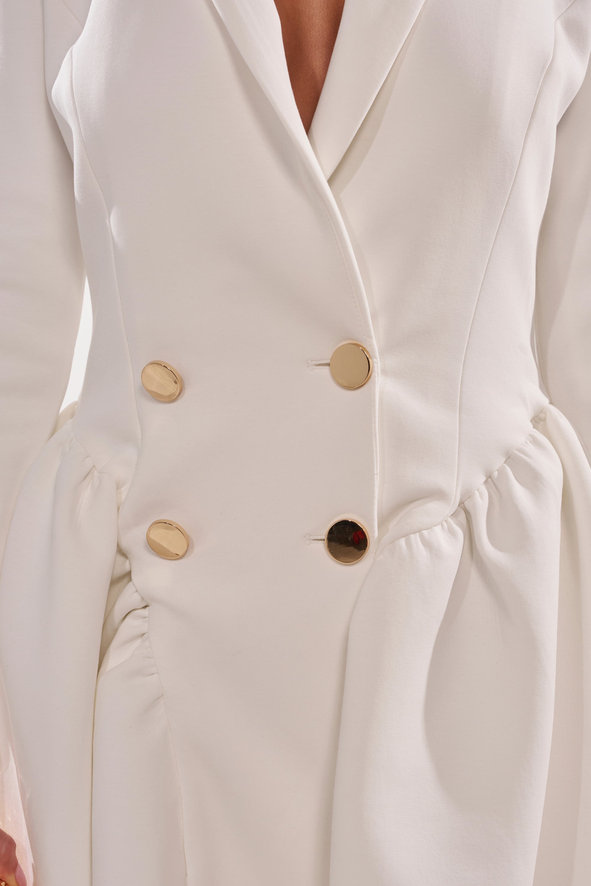 A close-up of the HBIC BLAZER MINI DRESS IN WHITE, featuring four large gold buttons, ruched side detailing, and a chic mini skater silhouette. 6