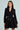 A woman stands against a light background in an HBIC BLAZER MINI DRESS, featuring gold buttons and a black, double-breasted design. Her long, straight hair complements her neutral expression, while the peplum hem adds flair to the dress's flared skirt starting at the waist.