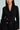 A woman in the HBIC BLAZER MINI DRESS, a black double-breasted coat with gold buttons and structured fabrication, featuring ruched waist detailing against a light gray background.