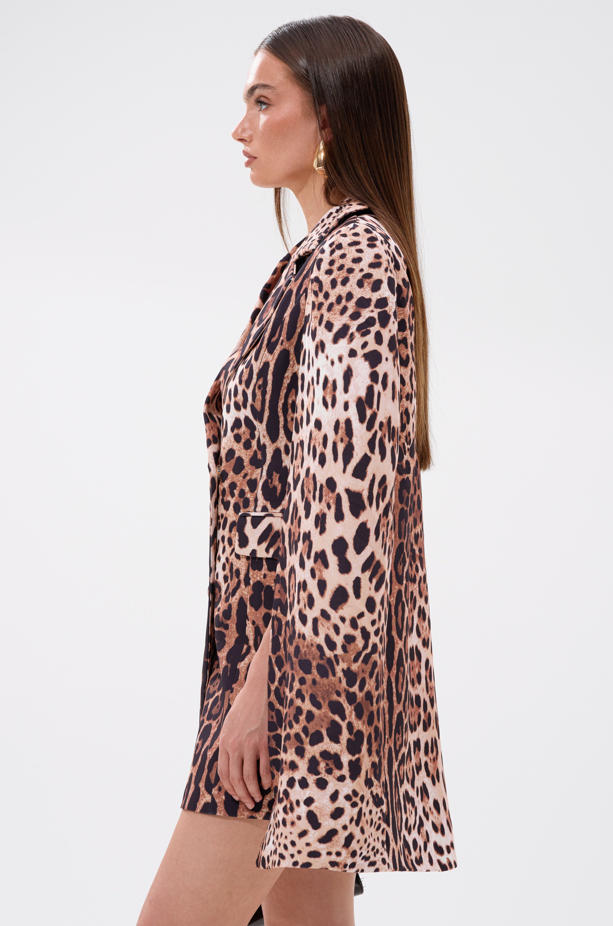A woman with straight brown hair stands in profile against a plain light background, wearing the AMINAH LEOPARD PRINT BLAZER DRESS featuring long sleeves and a mini length.