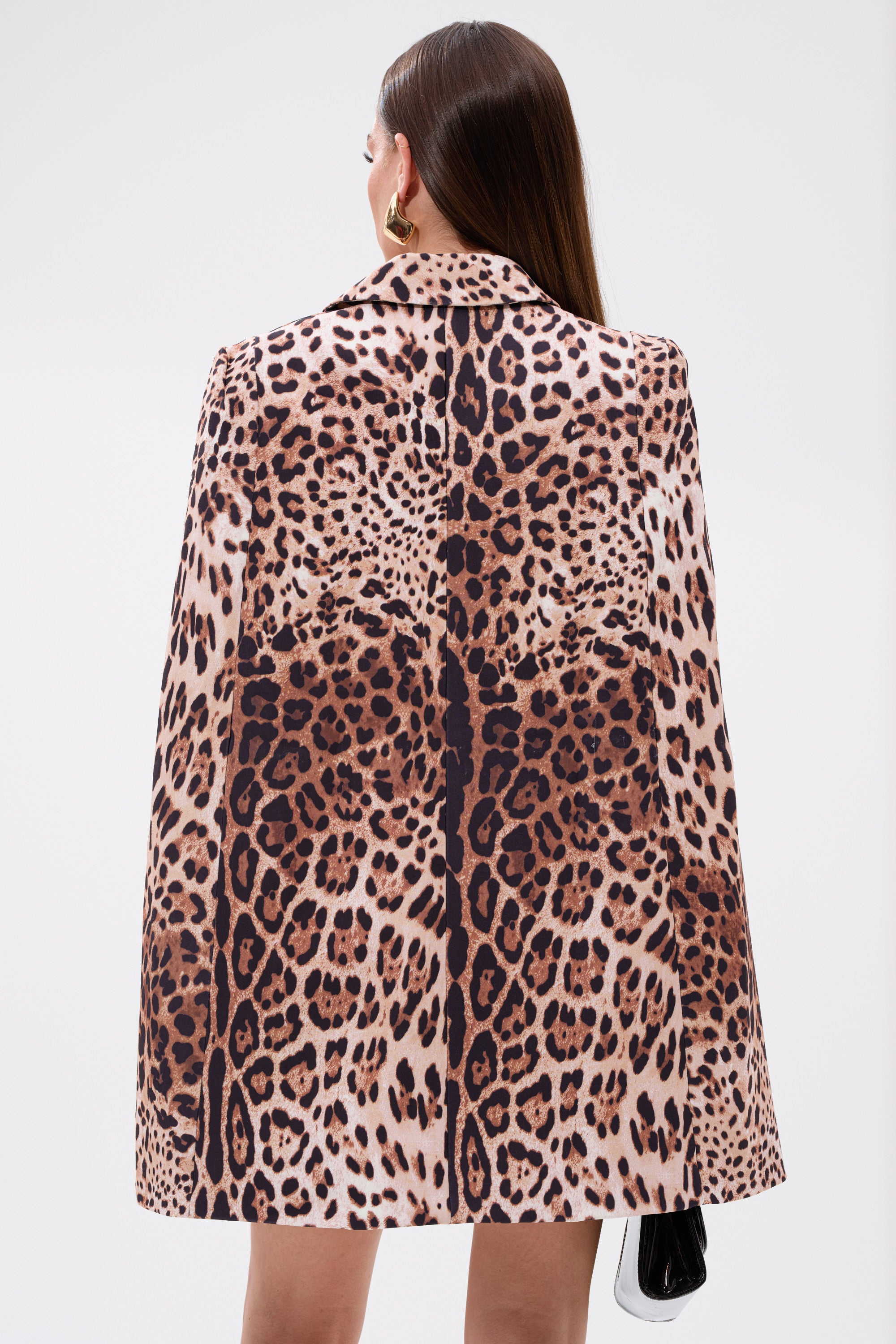 A woman with long straight brown hair, seen from the back against a white background, wears the AMINAH LEOPARD PRINT BLAZER DRESS and gold hoop earrings, holding a small black purse.