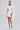 A woman exudes confidence in the A LA MODE MINI BLAZER DRESS IN WHITE, featuring a chic bodycon mini silhouette, styled with gold bangles and white platform heels against a plain background.