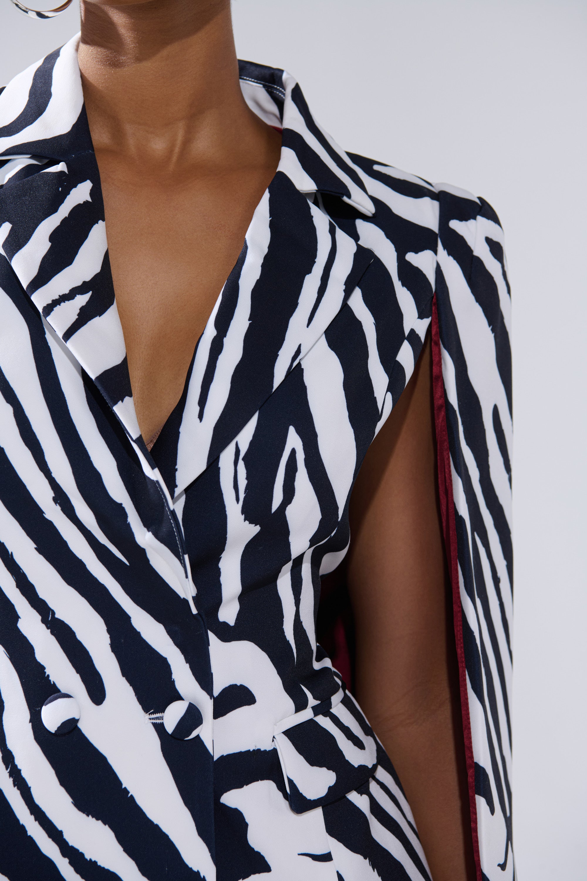 A close-up of a person wearing the WILD SIDE PRINTED BLAZER DRESS, featuring a black-and-white zebra pattern, deep neckline, and large lapels, photographed from shoulders to waist against a plain background.