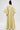 A person stands facing away, wearing the VENICE BROCADE PUFF SLEEVE DUSTER—a long, flowy dress with puff sleeves and a yellow and light blue floral brocade pattern—against a plain white background.