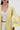 A woman wears the VENICE BROCADE PUFF SLEEVE DUSTER in yellow and light blue with voluminous sleeves, paired with a white ruched crop top and high-waisted pants. Only her lower face and torso are visible, giving the chic look a touch of vintage charm.