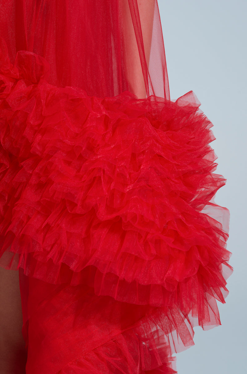 Zoom in on the ARI Tulle Ruffle High Low Mini Dress in Red, featuring ruffled, layered tulle that offers a voluminous and flowing texture. Perfect for a red-carpet look with each swirl against a light backdrop.