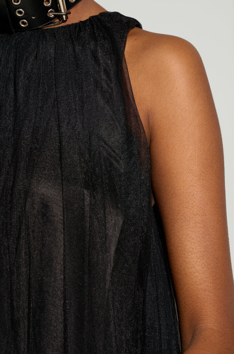 Close-up of a person wearing the ARI TULLE RUFFLE HIGH LOW DRESS IN BLACK, featuring sheer fabric and tulle ruffle detailing, paired with a wide black choker adorned with metal rings. The emphasis is on the texture of the fabric and the person's shoulder.
