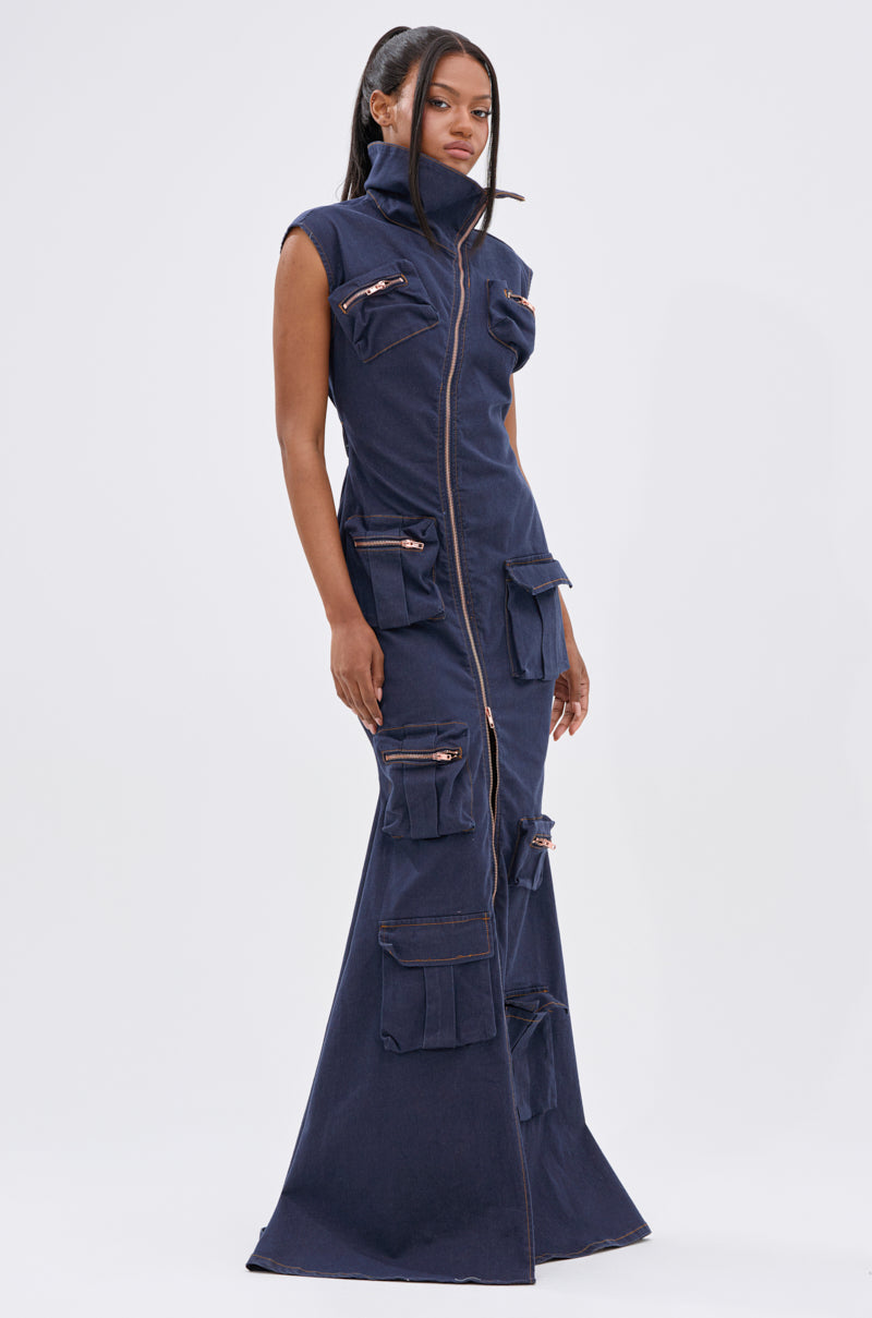A woman stands against a white background wearing the DONT MESS WITH ME COLLARED DENIM MAXI DRESS, a sleeveless dark wash denim maxi with a high collar, front zipper, and multiple utility pockets on the bodice and skirt.