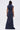 A woman with straight hair stands facing away against a light background, wearing the DONT MESS WITH ME COLLARED DENIM MAXI DRESS featuring a high collar and gathered waist.
