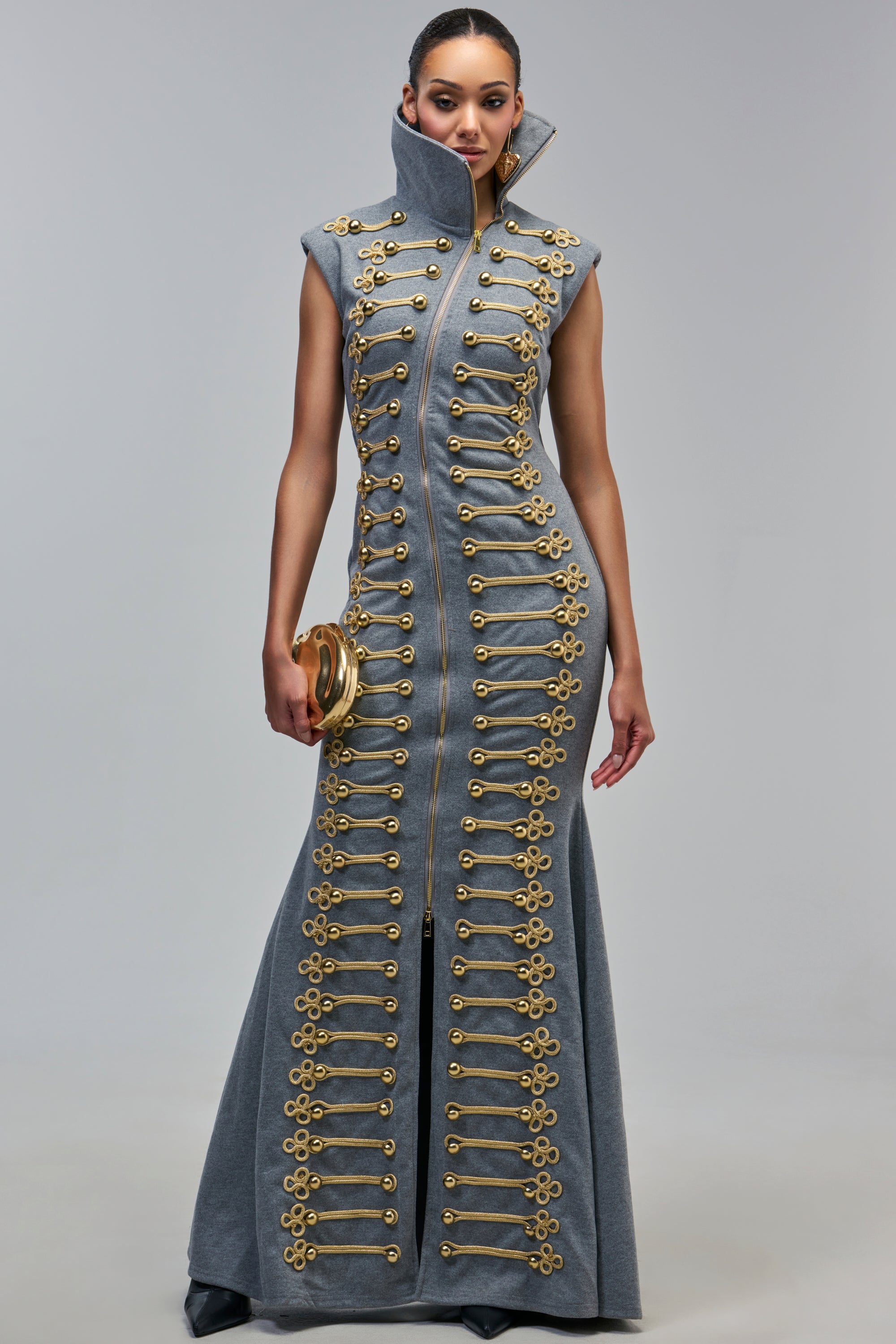 DON’T MESS WITH ME COLLARED CADET MAXI DRESS in gray, featuring a high collar, a front zipper, and rows of gold military-style embellishments, paired with a gold clutch.