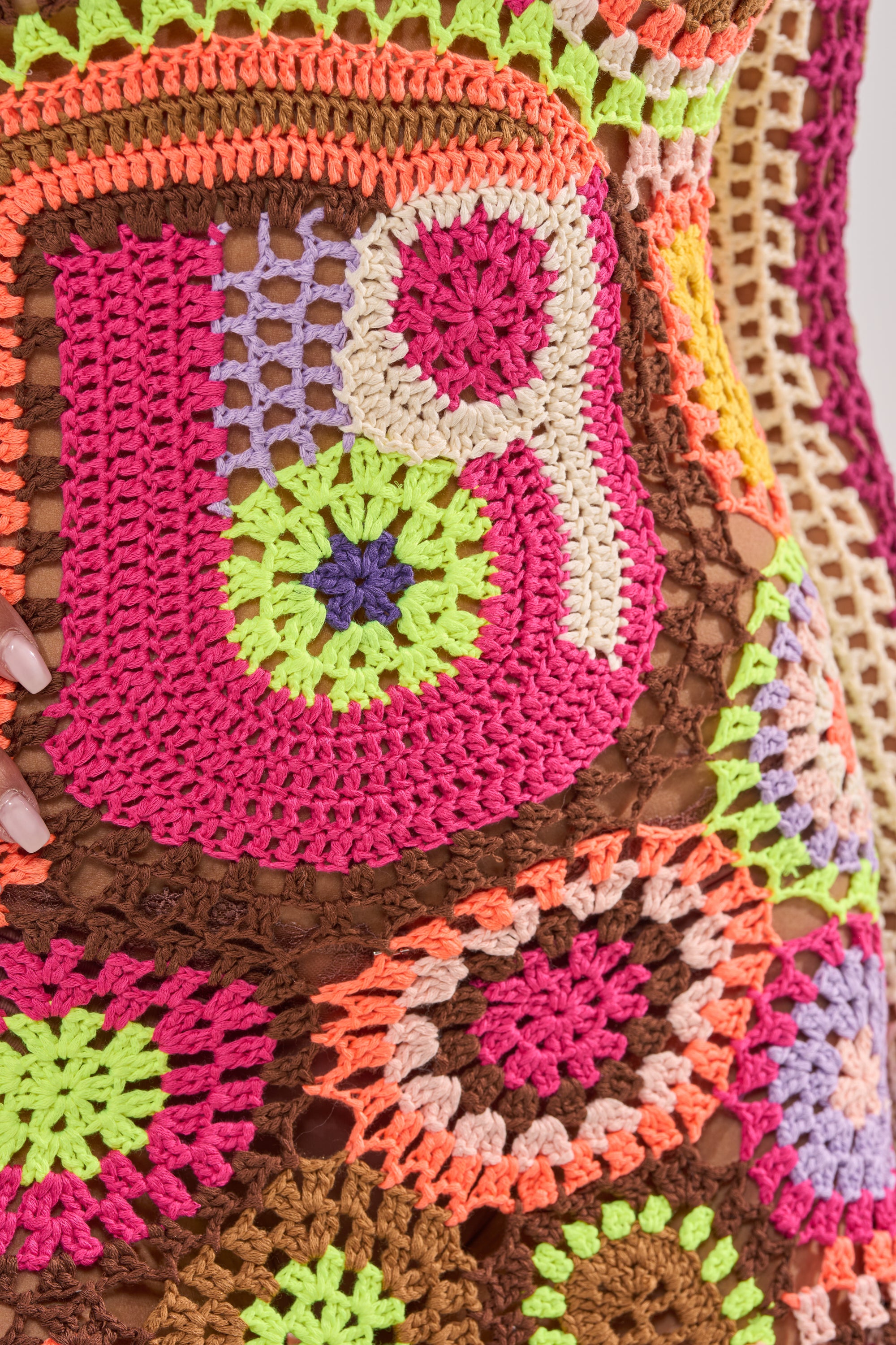 Close-up of the CABANA CROCHET MINI DRESS featuring intricate patchwork in pink, green, purple, orange, and brown yarn with circular and geometric designs on a mesh background. 7