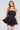A woman in the Felt Cute Poplin Mini Dress in blue pinstripe holds the hem of her short, flared skirt. She accessorizes with large hoop earrings, a pearl necklace, and white thigh-high stockings. Her blonde hair is loose as she stands against a plain gray background.