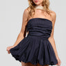 A woman in the Felt Cute Poplin Mini Dress in blue pinstripe holds the hem of her short, flared skirt. She accessorizes with large hoop earrings, a pearl necklace, and white thigh-high stockings. Her blonde hair is loose as she stands against a plain gray background.