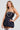 A woman poses confidently in the "Felt Cute Poplin Mini Dress" in blue pinstripe, featuring a strapless design and balloon skirt, complemented by layered pearl necklaces and lace thigh-high stockings against a neutral background.