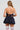 A person with long hair is facing away, wearing the Felt Cute Poplin Mini Dress in blue pinstripe. The outfit, styled to resemble a mini dress, is accessorized with layered necklaces and paired with thigh-high white stockings against a plain, light-colored background.