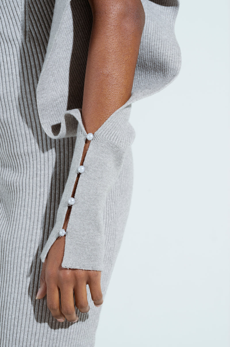 A person wearing the Off to Brunch Knit Midi Dress in Heather Grey displays understated elegance, with decorative buttons along the sleeve seam complementing a curve-hugging silhouette. Their hand rests naturally by their side against a plain, light-colored background.