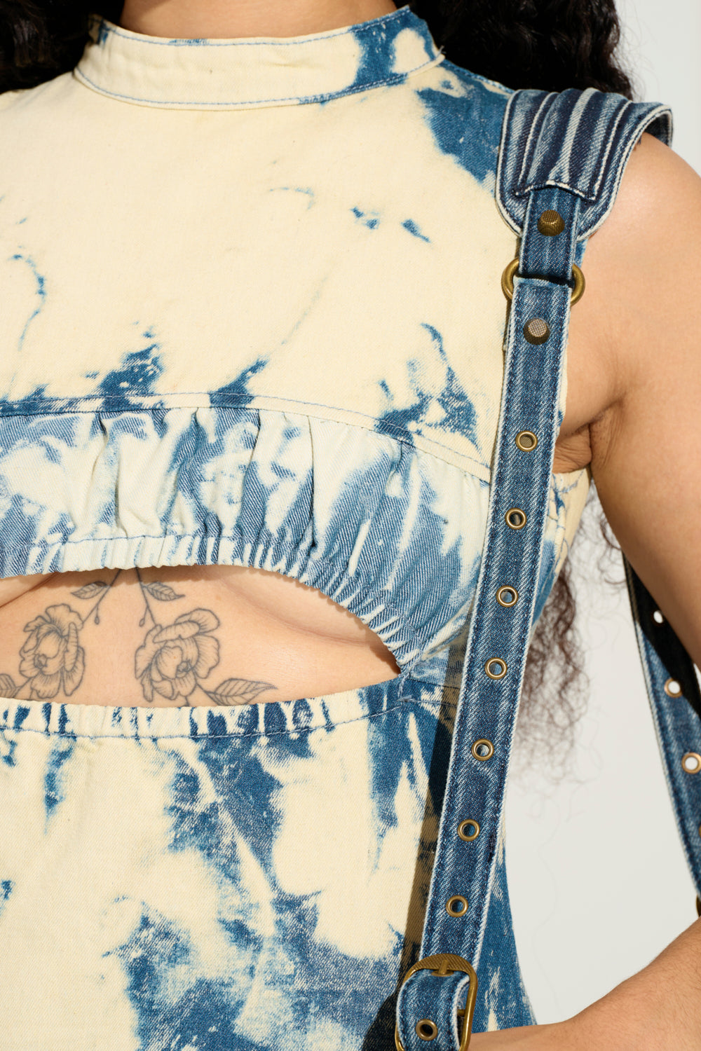 A close-up showcases someone in the STREET STYLE ACID WASH MAXI DRESS, highlighted by a tie-dye pattern and a denim strap with metal eyelets. The dress's cut-out section reveals a floral tattoo, contributing to its edgy street style aesthetic.