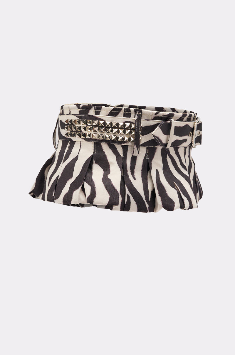 The ZEBRA PEPLUM BELT SKIRT is a black and white zebra print pleated mini skirt with a wide adjustable belt adorned with metallic square studs and a large buckle.