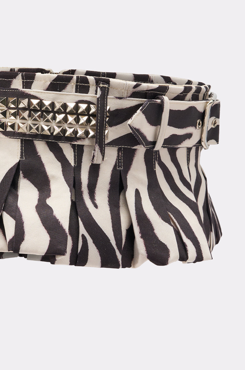 The ZEBRA PEPLUM BELT SKIRT is a black and white zebra-print pleated skirt with a matching adjustable belt, silver studs, and a rectangular buckle.
