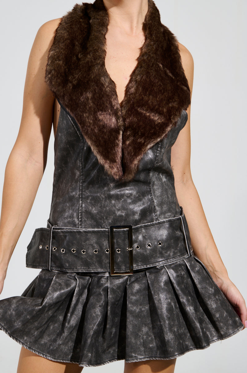 The person is exuding sophistication in a sleeveless, gray textured dress that boasts a flared skirt and a prominent belt. The outfit's top features a wide fur collar, reminiscent of the chic design found in the STEPPING OUT PU FUR TRIM MINI DRESS. The open-back style introduces an unexpected twist against the plain background.
