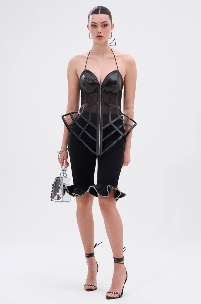 A woman stands facing forward in the DAINTY DETAILS RUFFLE HEM TAILORED SHORT, paired with a black structured corset top, strappy black heels, and a small silver handbag against a plain white background.
