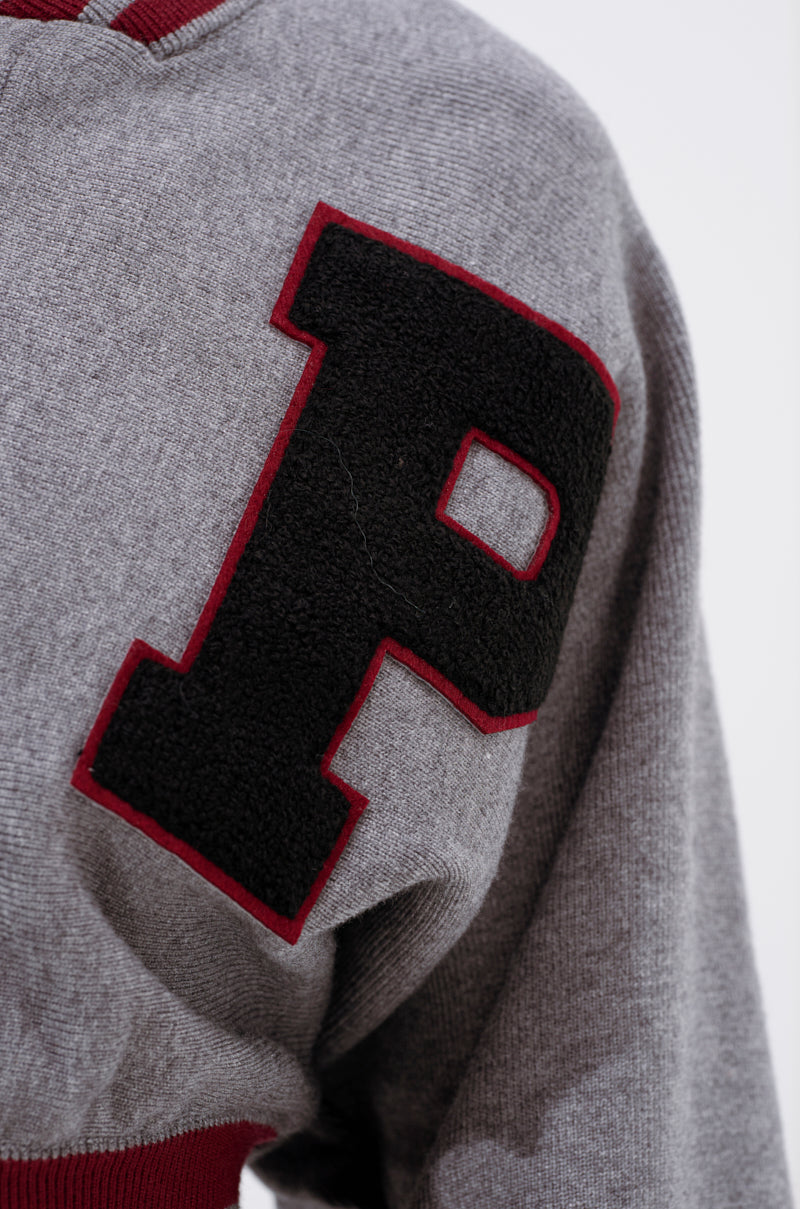 Close-up of the VARSITY TEAM BUTTON DOWN SWEATER IN HEATHER GREY, showcasing a large black "P" with a red outline sewn on the chest, letterman style. 8